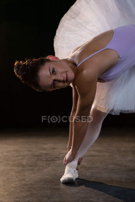 Portrait of female ballet dancer stretching before dancing in the studio — Stock Photo