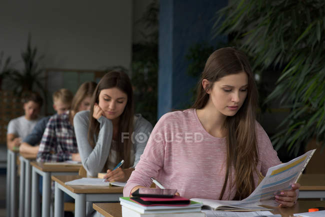 Студенты университета сидят за столом во время экзамена в классе — стоковое фото
