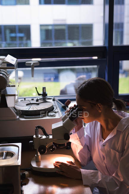 Female student using microscope while practicing experiment in lab — Stock Photo