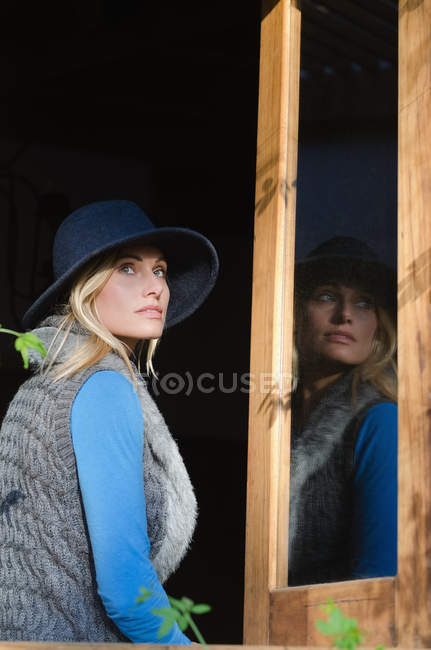 Задумчивая женщина смотрит в сторону, сидя на окне в туристическом курорте — стоковое фото