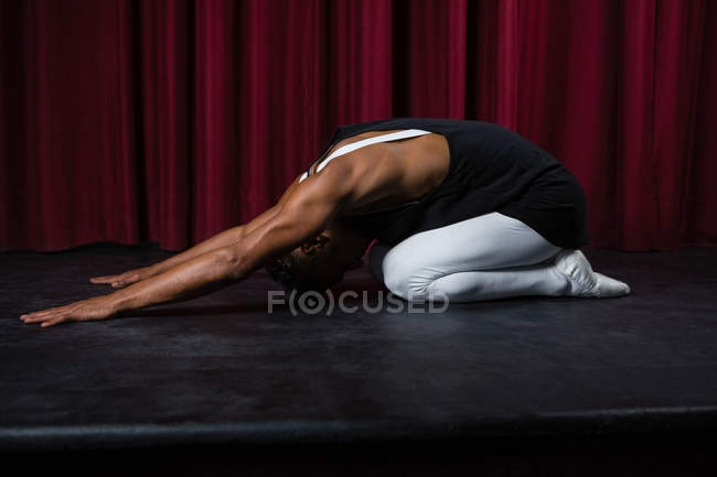 Bailarino realizando exercício de alongamento no palco — Fotografia de Stock