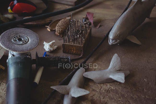 Metal fish and hand tool on worktop in workshop — Stock Photo