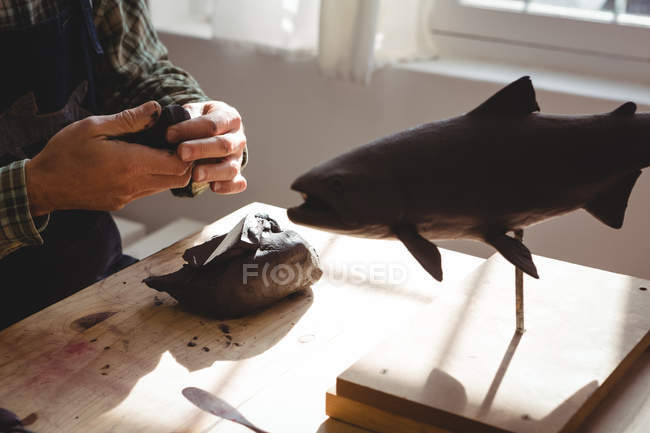Ремесленник, работающий над глиняной скульптурой в мастерской — стоковое фото