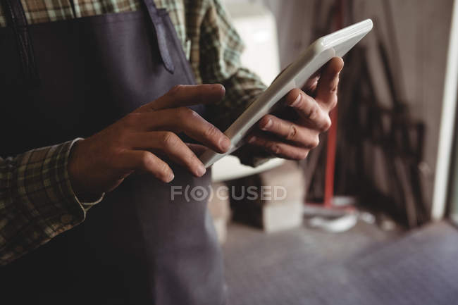 Mid-section of craftsman using digital tablet in workshop — Stock Photo