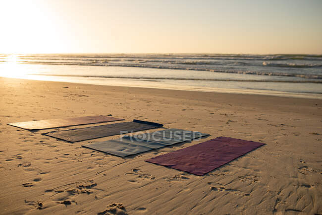 Vue générale de quatre tapis de yoga sur la plage par une journée ensoleillée avec une vue imprenable sur la mer calme. — Photo de stock