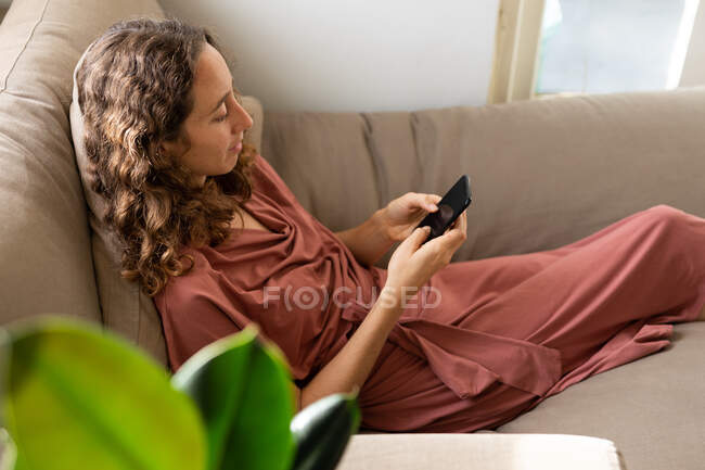 Кавказька жінка проводить час удома, користуючись своїм смартфоном. Стиль життя вдома ізольований, соціальна дистанція в карантині під час коронавірусу covid 19 пандемії. — стокове фото