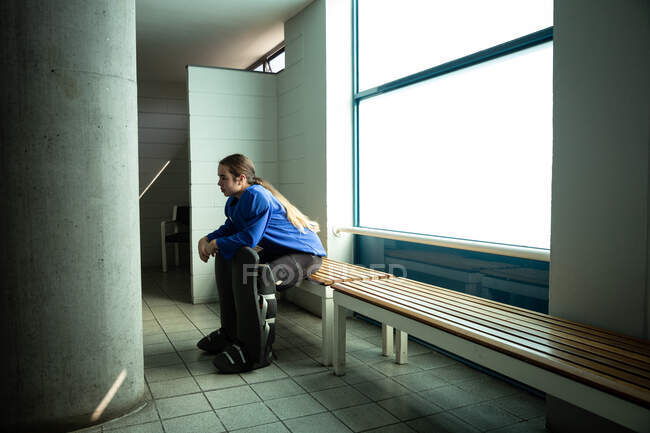 Кавказька хокеїстка готується до гри, сидить у мінливому приміщенні, фокусує увагу — стокове фото