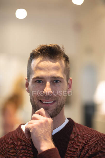 Portrait of happy Caucasian male business creative working in a casual modern office, smiling and looking at camera, touching his chin — Stock Photo