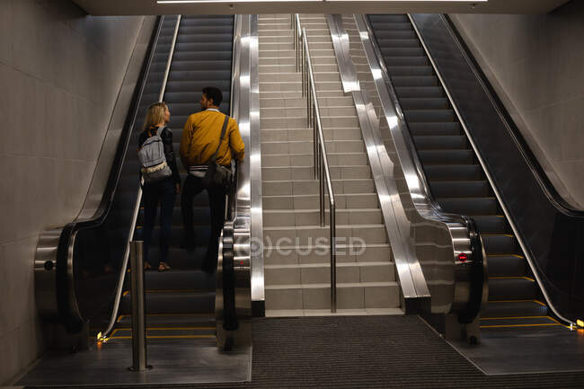 Vue arrière d'un couple caucasien dans la ville, montant dans une station de métro avec un escalator. — Photo de stock