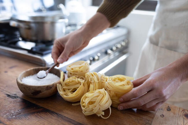 Nahaufnahme einer Frau im Pullover, die Pasta für ihr Mittagessen zubereitet. Soziale Distanzierung und Selbstisolierung in Quarantäne. — Stockfoto