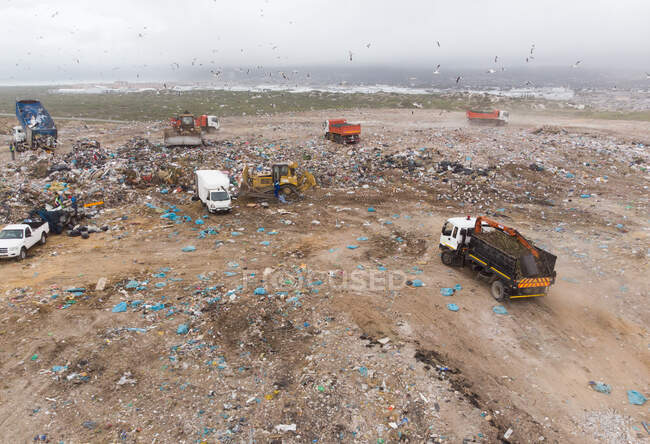 Drone tiro de veículos que trabalham, limpando e entregando lixo empilhado em um aterro cheio de lixo. Questão ambiental global da eliminação de resíduos . — Fotografia de Stock