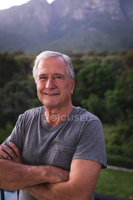 Portrait close up of a handsome senior Caucasian man enjoying his retirement, in a garden in the sun looking to camera smiling with arms crossed, self isolating during coronavirus covid19 pandemic — Stock Photo