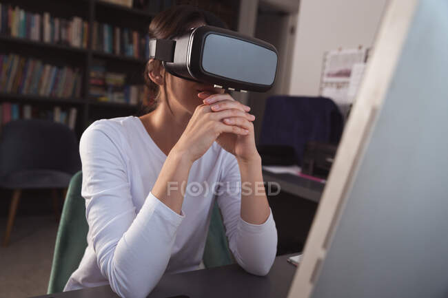 Mixed race woman spending time at home self isolating and social distancing in quarantine lockdown during coronavirus covid 19 epidemic, sitting at desk wearing VR headset working from home — Stock Photo