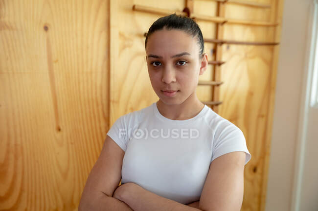 Портрет впевненого щасливого підлітка змішаної раси жіночого дзюдоїстки в білій футболці, стоячи в спортзалі і дивлячись прямо в камеру . — стокове фото