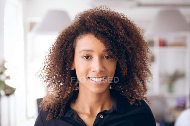 Портрет крупним планом щасливої змішаної гонки бізнес-леді, що працює в сучасному офісі, дивлячись прямо на камеру і посміхаючись — стокове фото