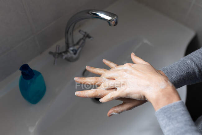 Крупним планом середня частина жінки, одягнена в сірий светр, миє руки рідким милом. Соціальне дистанціювання та самоізоляція в карантинному блокуванні . — стокове фото