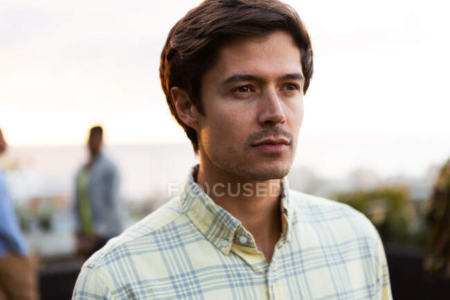 Vista frontal de perto de um homem caucasiano pendurado em um terraço em um dia ensolarado, olhando para longe da câmera — Fotografia de Stock
