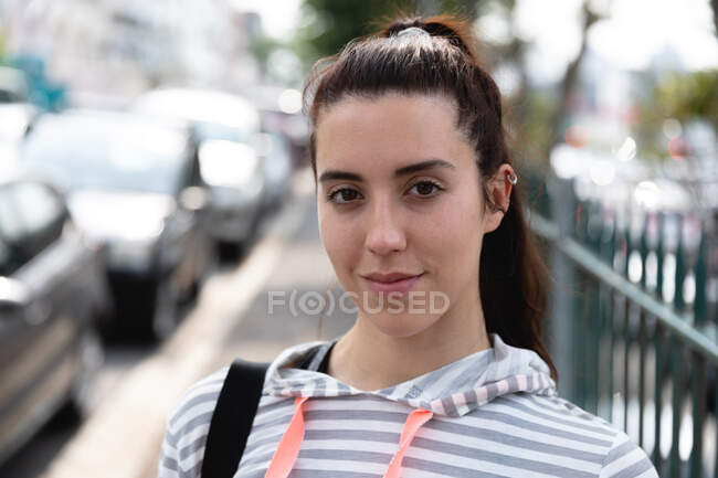 Porträt einer fitten Kaukasierin auf der Straße auf dem Weg zum Fitnesstraining an einem bewölkten Tag, lächelnd in die Kamera blickend — Stockfoto
