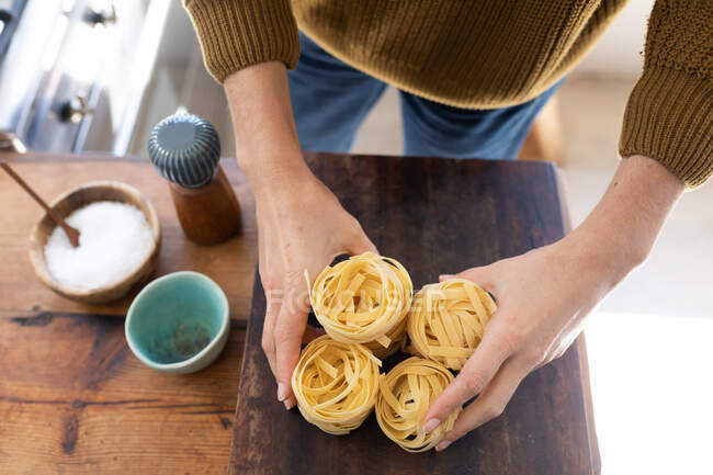 Feche no meio da seção de mulher vestindo uma camisola, preparando macarrão para seu almoço. Distanciamento social e auto-isolamento em quarentena . — Fotografia de Stock