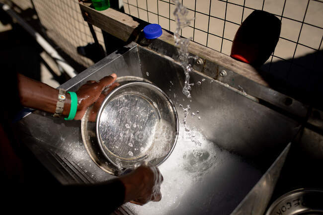 Side view mid section of a female volunteer at an animal shelter in a room washing bowls during preparing food for their dogs. — Stock Photo