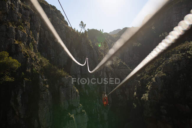 Vista posteriore dell'uomo caucasico godendo del tempo nella natura, zip fodera in una giornata di sole in montagna. Divertente weekend di vacanza avventura. — Foto stock