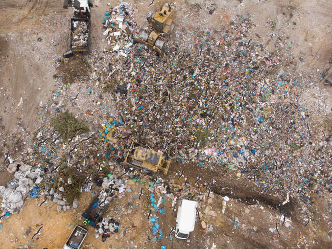 Drone tiro de veículos que trabalham, limpando e entregando lixo empilhado em um aterro cheio de lixo. Questão ambiental global da eliminação de resíduos . — Fotografia de Stock