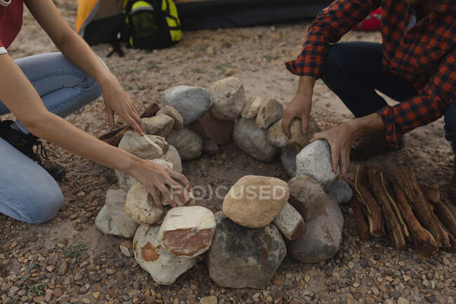 High angle view close up of couple having a good time on a trip to the mountains, building a campfire — Stock Photo