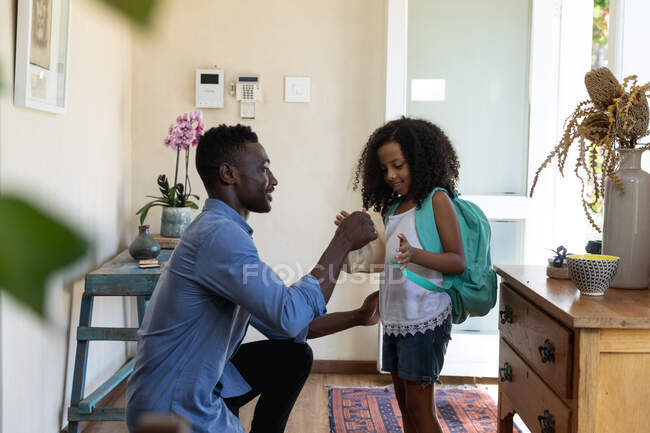 Afroamerikanerin und ihr Vater verbringen Zeit zu Hause, bereiten sich auf den Schulbesuch vor, Vater schenkt seiner Tochter eine Tüte mit einem Imbiss. — Stockfoto