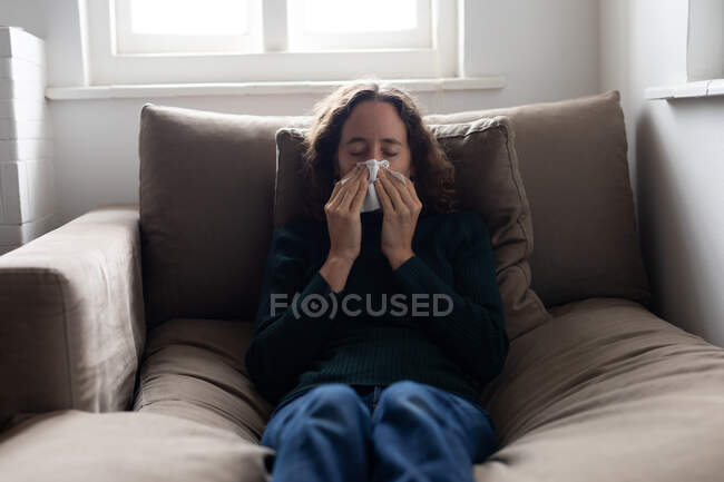 Eine Kaukasierin verbringt Zeit zu Hause und pustet sich die Nase zu. Lebensstil zu Hause isolierend, soziale Distanzierung in Quarantäne während Coronavirus covid 19 Pandemie. — Stockfoto