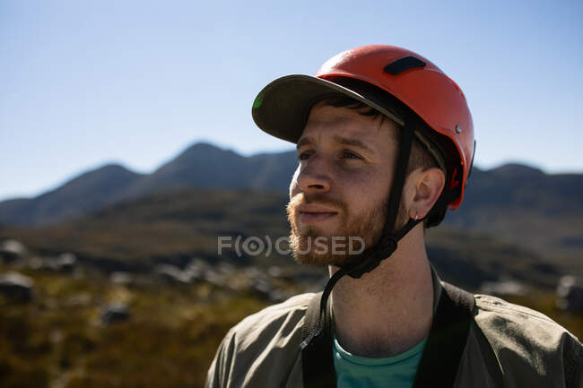 Vista frontal de perto no homem caucasiano aproveitando o tempo na natureza, usando equipamento de tirolesa em um dia ensolarado nas montanhas — Fotografia de Stock