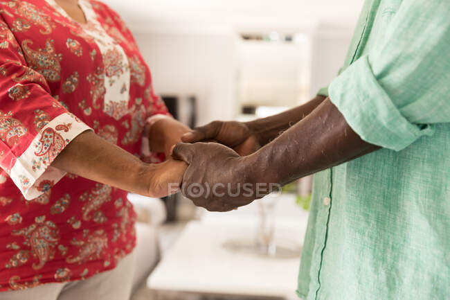 Mid section of couple spending time at home together, social distancing and self isolation in quarantine lockdown during coronavirus covid 19 epidemic, standing and holding hands — Stock Photo
