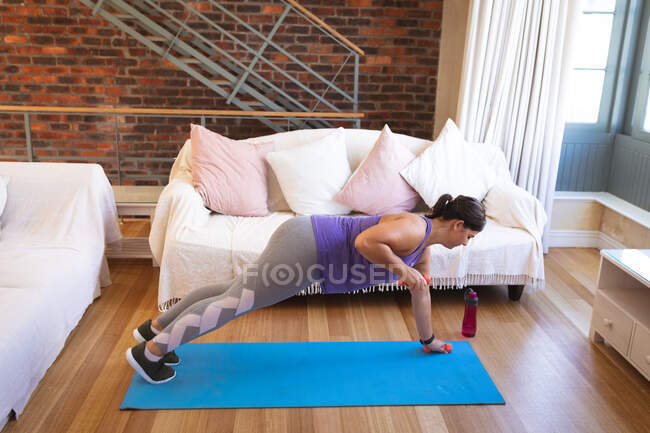 Vlogger mujer caucásica en casa en su sala de estar, demostrando ejercicios para su blog en línea. Distanciamiento social y autoaislamiento en cuarentena. - foto de stock