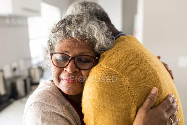 A senior African American couple spending time at home together, social distancing and self isolation in quarantine lockdown during coronavirus covid 19 epidemic, embracing, smiling — Stock Photo