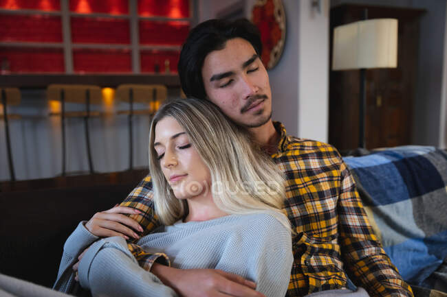 Front view close up of a young mixed race man and a young Caucasian woman enjoying time at home, sitting in their living room, embracing while sleeping. — Stock Photo