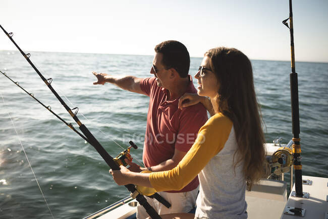 Um homem caucasiano e sua filha adolescente segurando varas de pesca e falando — Fotografia de Stock