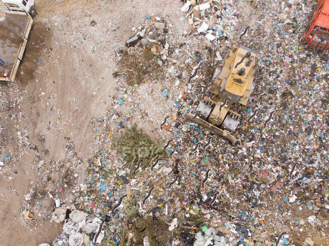 Tiro de aviones no tripulados de excavadoras trabajando y limpiando basura apilada en un vertedero lleno de basura. Cuestión medioambiental mundial de la eliminación de residuos. - foto de stock
