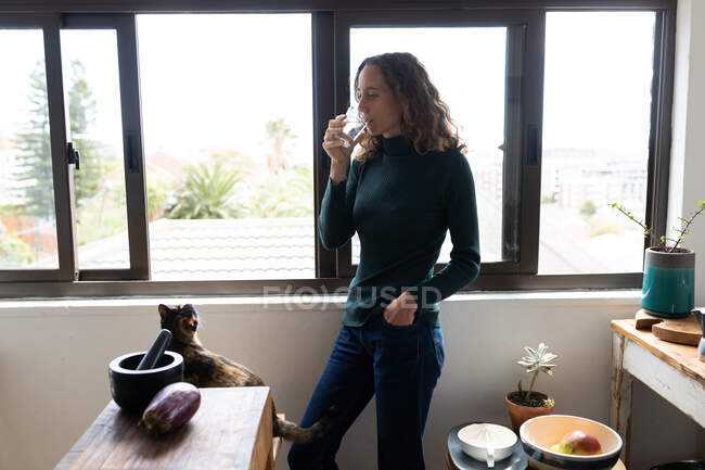 A Caucasian woman spending time at home, drinking water. Lifestyle at home isolating, social distancing in quarantine lockdown during coronavirus covid 19 pandemic. — Stock Photo