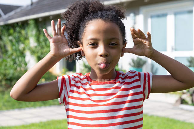 African American girl social distancing at home during quarantine lockdown, spending time in a garden and having fun, looking straight into a camera. — Stock Photo