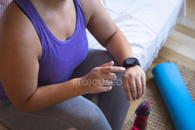 Mid section of female vlogger at home in her sitting room, preparing to demonstrate exercises for her online blog, using her smartwatch. Social distancing and self isolation in quarantine lockdown. — Stock Photo