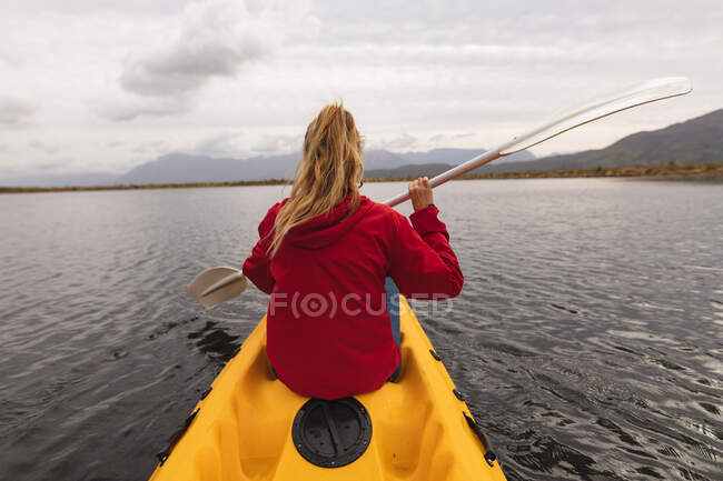 Rear view of a Caucasian woman having a good time on a trip to the mountains, kayaking on a lake, enjoying her view — Stock Photo