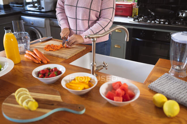 Sección media de la blogger femenina en casa en su cocina, demostrando la preparación de recetas de alimentos para su blog en línea. Distanciamiento social y autoaislamiento en cuarentena. - foto de stock