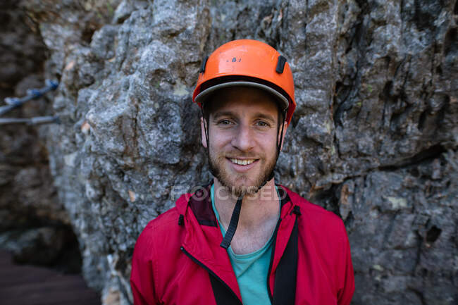 Portrait d'homme caucasien profitant du temps dans la nature, portant un équipement de tyrolienne, souriant par une journée ensoleillée dans les montagnes. Fun week-end aventure vacances. — Photo de stock