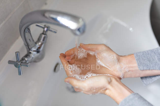 Chiudere metà sezione della donna che indossa maglione grigio, lavandosi le mani con sapone liquido. Distanziamento sociale e autoisolamento in quarantena. — Foto stock