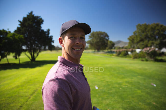 Портрет кавказького чоловіка на полі для гольфу в сонячний день з блакитним небом, посміхаючись до камери — стокове фото