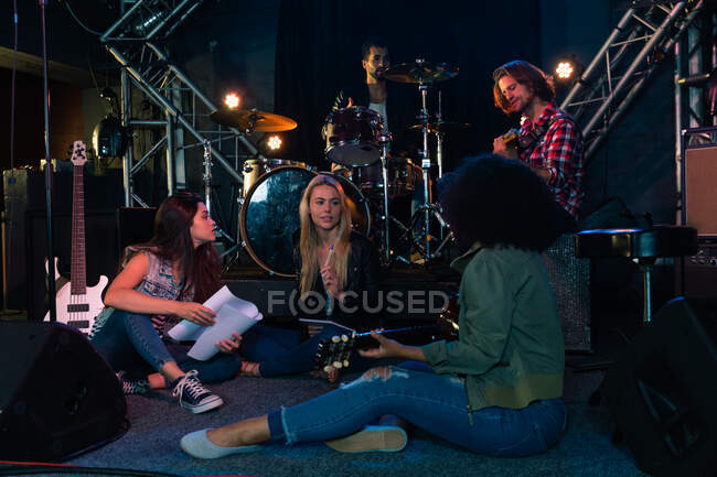 Seitenansicht einer multiethnischen Gruppe von Musikern und Sängerinnen, die vor einem Auftritt gemeinsam an einem Musikort proben und an einem Lied arbeiten — Stockfoto