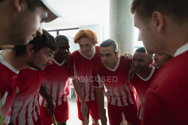 Side view close up of a teenage multi-ethnic group of male field hockey players in a huddle in the changing room, preparing before a game, focusing — Stock Photo