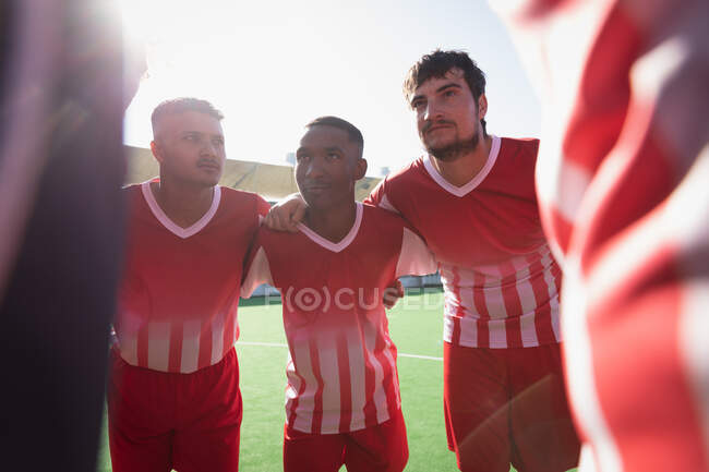 Front view of a multi-ethnic group of teenage male field hockey players preparing before a game, in a huddle on the pitch, interacting on a sunny day — Stock Photo