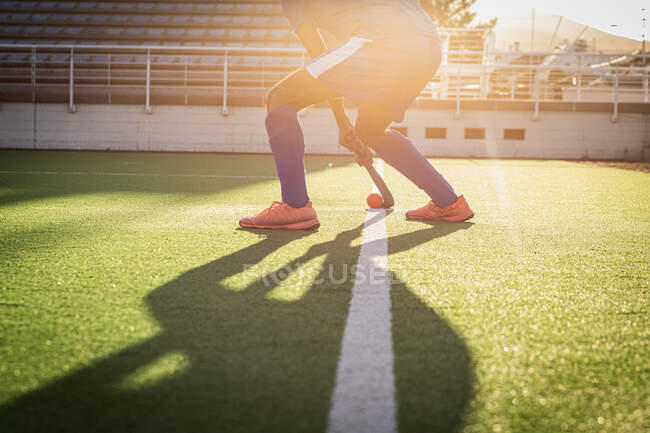 Боковой вид низкого сектора полевого игрока в действии на поле, готовящегося в солнечный день отбить мяч от средней линии, с подсветкой — стоковое фото