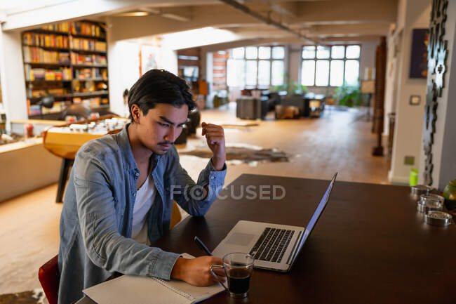Self isolation in lockdown quarantine. side view of a young mixed race man, sitting in the living room, using his laptop while working. — Stock Photo