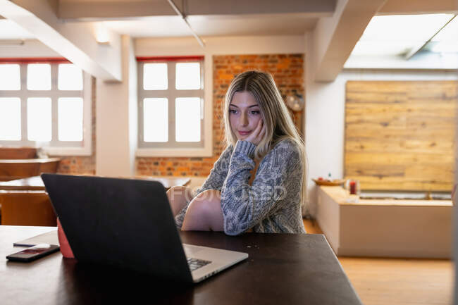 Selbstisolierung in Quarantäne. Frontansicht einer jungen kaukasischen Frau, die im Wohnzimmer sitzt und während der Arbeit ihren Laptop benutzt. — Stockfoto